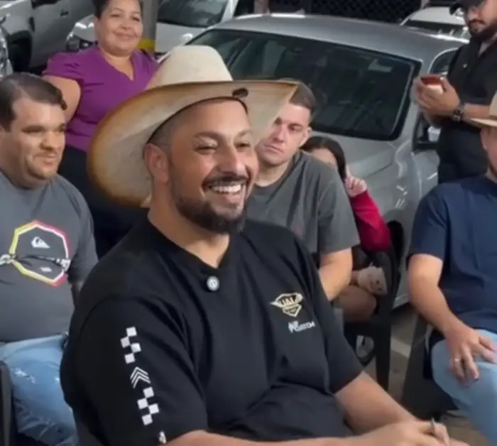 Homem de chapéu sorrindo numa roda de negociação de carro